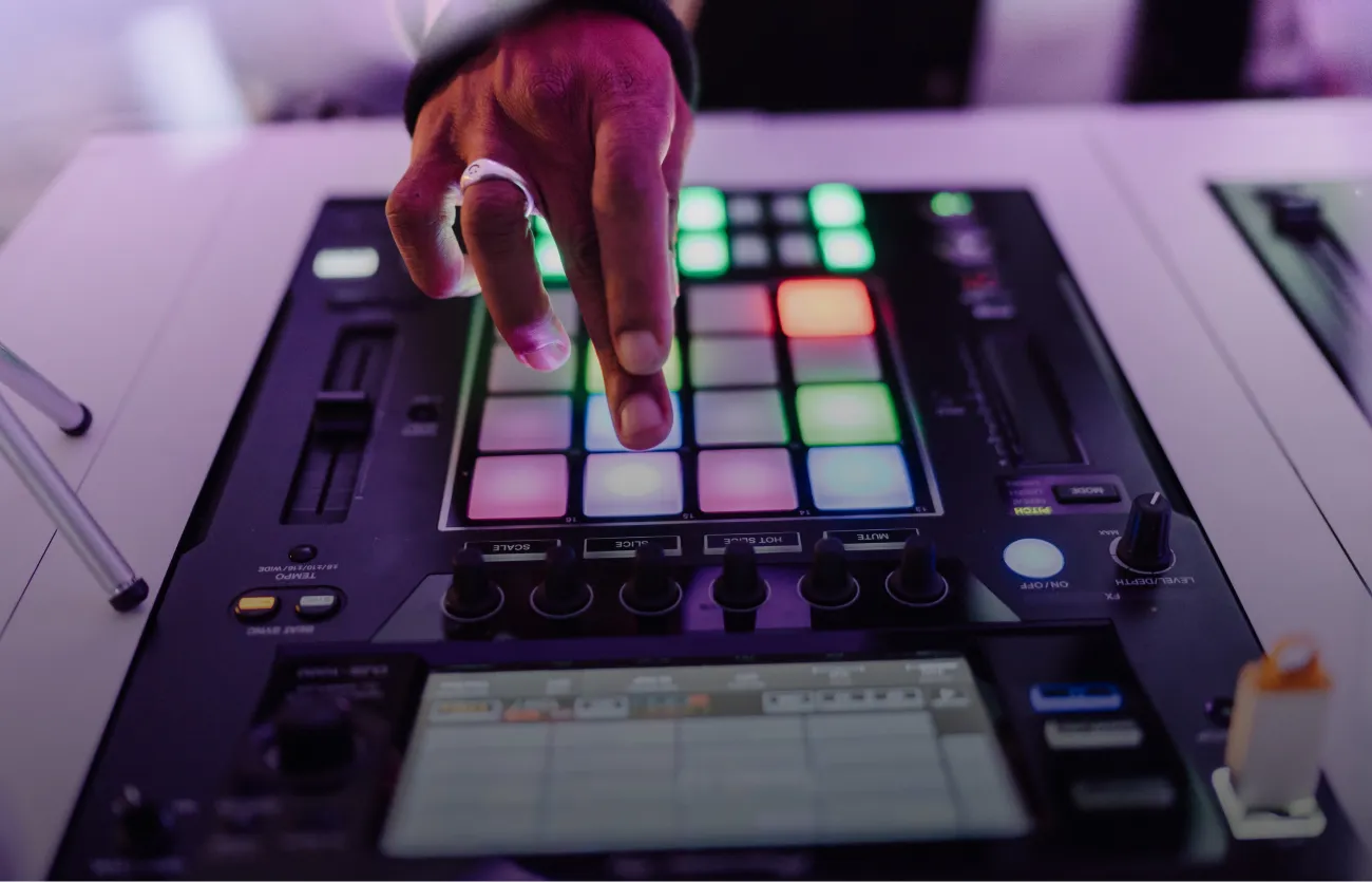 A DJ drums the pads on an advanced DJ sampler during a hybrid DJ set